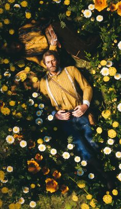 a man laying on the ground surrounded by flowers