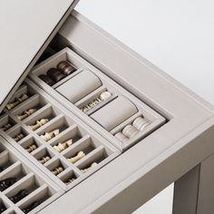 an open drawer with chess pieces and other items in it on a white table top