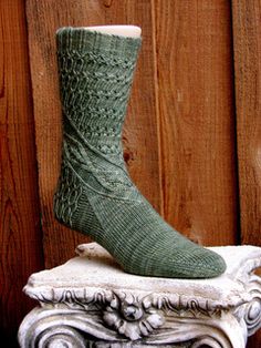 a pair of green socks sitting on top of a white pedestal next to a wooden fence