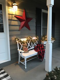 a white bench sitting on top of a porch next to a christmas tree and lights