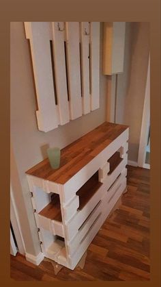 a wooden table sitting on top of a hard wood floor next to a white wall