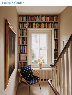 a chair sitting in front of a window next to a book shelf filled with books