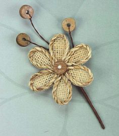 a flower made out of woven material with wooden buttons on the center and two stems attached to it