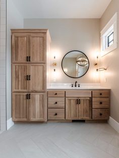 a bathroom with wooden cabinets and a round mirror