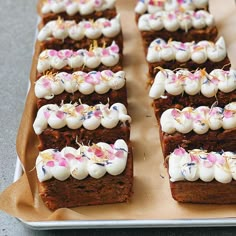 several pieces of cake with white frosting and sprinkles on them sitting on a tray