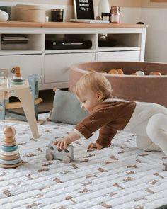 a toddler plays with his toys on the bed in their nursery room at home