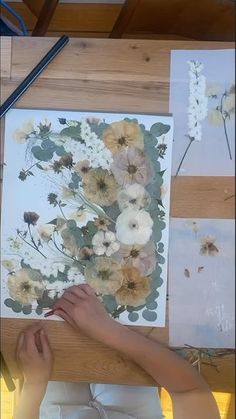 a person is painting flowers on a piece of paper