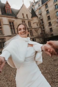 a woman in a white wedding dress holding the hand of another person's hand