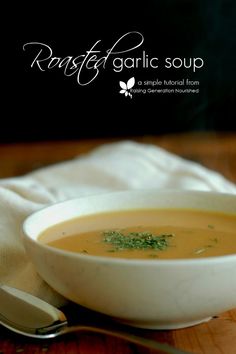 a white bowl filled with soup sitting on top of a wooden table next to a spoon