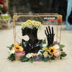 a black mannequin with flowers on it's head in front of a sign