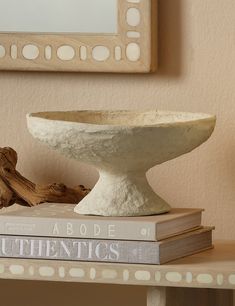 a white bowl sitting on top of two books