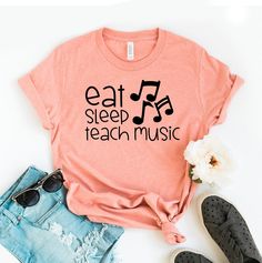 "Eat Sleep Teach Music T-shirt, Teaching Shirt, Musician Tee, School Gift, Music Lover Shirt, Teacher Tee, School Tops, Teacher Gift, Teacher Shirts, Teacher T-shirts, Teacher Tees, Teacher Appreciation, Gift For Teacher, Funny Teacher Shirt, Cute Teacher Tee, Teacher Love Shirt, Best Teacher Shirt, Love Teachers, Caring Teacher, New Teacher Gift This updated unisex essential fits like a well-loved favorite. Super soft cotton and excellent quality print makes one to fall in love with it over and over again. ------------- Fabrication ------------- 100% Combed ring spun cotton Made by specially treating the cotton fibers before spinning them into yarn. The result is stronger and smoother fabric. ------------- Unisex T-shirt Size Chart ------------- XS - - 27\" Length and 18\" Width S - 28\" Music-themed Slogan T-shirt With Short Sleeves, Music-themed Cotton Top With Text Print, Music-themed Slogan Crew Neck Top, Music-themed Slogan Tops With Crew Neck, Music-themed Short Sleeve Tops With Text Print, Music-themed Slogan Top With Crew Neck, Music-themed Tops With Text Print And Short Sleeves, Music-themed Letter Print T-shirt For Music Festivals, Music-themed Text Print Short Sleeve Tops