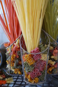 there are two vases filled with different types of noodles on the table and one is holding some type of pasta