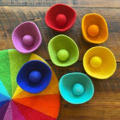 colorful felt bowls with balls in them on a wooden surface