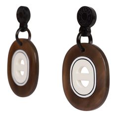 two brown and white buttons are attached to black metal hooks, one with a button on it