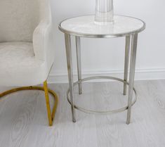 a white chair sitting next to a table with a vase on it's top