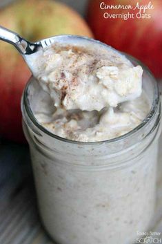 a spoon full of oatmeal sitting in a jar next to an apple