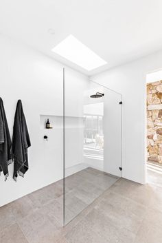 a bathroom with two towels hanging on the wall and a glass shower door in front of it