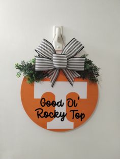 an orange and white door hanger with a bow on it that says good ol'rocky top