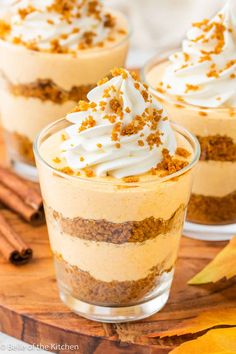 three desserts in small glass dishes on a wooden board with cinnamon sticks and leaves