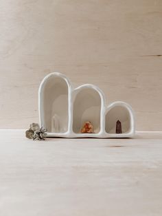 three white vases sitting on top of a wooden table next to each other with small objects in them