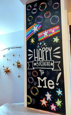 a happy birthday chalkboard with stars and rainbows on it in the corner of a room