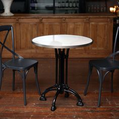 two black chairs and a white table in a room with wood paneled flooring