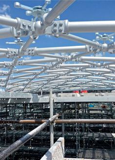 an array of metal structures with sky in the backgrouds and blue skies above them