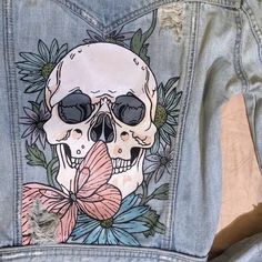 the back of a jean jacket with a skull and flowers on it