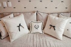 four white pillows with black bows on them sitting on a couch in front of a wall