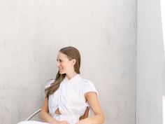 a woman sitting on the ground with a basket in her hand and smiling at someone behind her