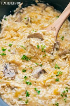 a wooden spoon in a pot filled with rice and mushrooms