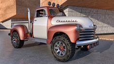 an old red and white truck parked in front of a building