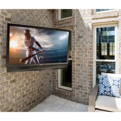 a large television mounted to the side of a brick building