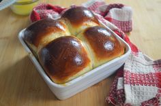 four hot cross buns in a baking dish on a wooden table