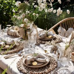 the table is set with plates, cups and vases filled with flowers on it