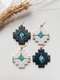 three pairs of earrings with blue and white designs on them next to some wheat stalks