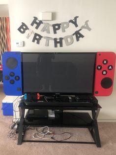 a flat screen tv sitting on top of a wooden stand in front of a happy birthday sign