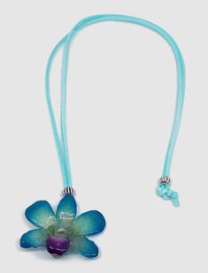 a necklace with a flower on it and a blue cord hanging from the end,