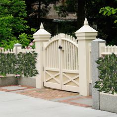 a white gate and fence with pink flowers in the background