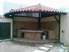 an outdoor bbq and grill area is shown in front of a building with tiled roof