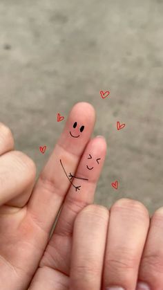 someone has drawn a smiley face on their fingers with hearts and arrows in the background