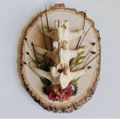 an animal's skull and flowers are on a wooden slice that has been cut into smaller pieces