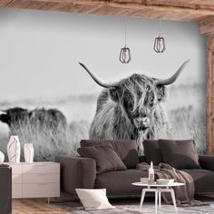 a living room with a cow wall mural in the center and a couch on the other side