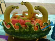 a watermelon boat with bananas, melons and other fruits in the shape of dolphins