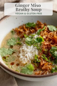 a white bowl filled with meat and rice next to cilantro on top of a table