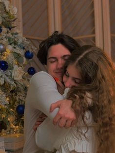 two women hugging each other in front of a christmas tree