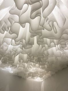 an abstractly designed ceiling in a room with light coming from the ceiling and white walls