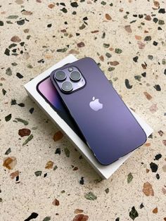 two purple iphones sitting on top of each other in front of a white box