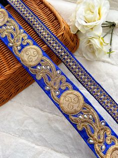 two blue and gold belts sitting on top of a basket next to a white flower